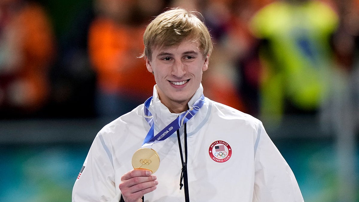 Jordan Stolz celebrating with gold medal on podium at speedskating event