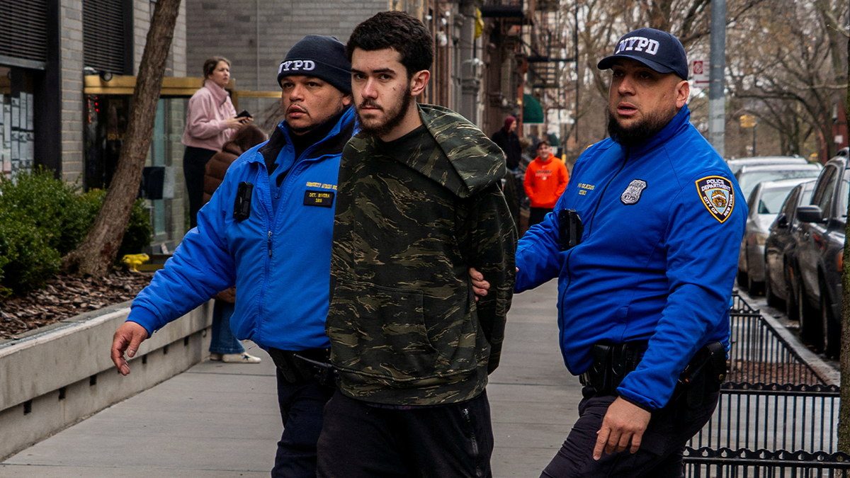 Ibrahim Kayumi in custody, flanked by two NYPD officers