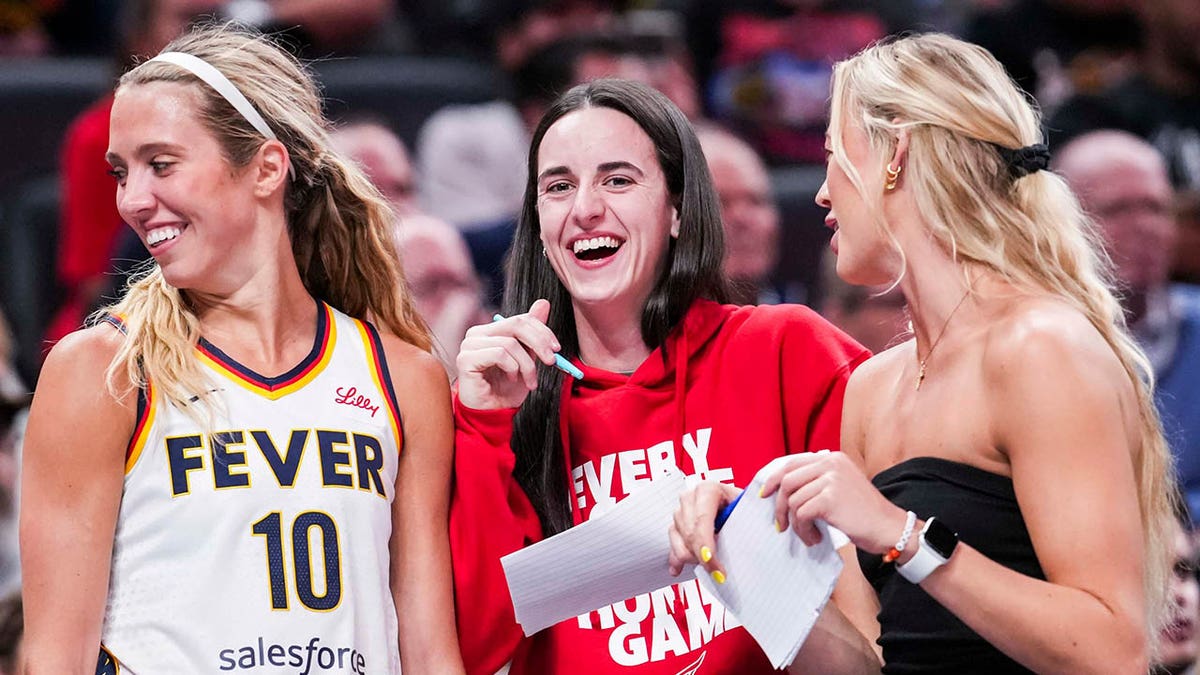 Indiana Fever guards Lexie Hull, Caitlin Clark, and Sophie Cunningham laughing near team bench