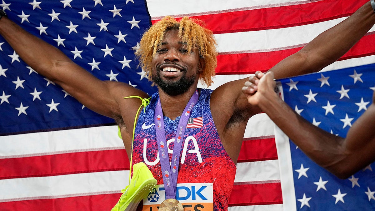 Noah Lyles posing with a flag after winning gold in men's 200 meters final