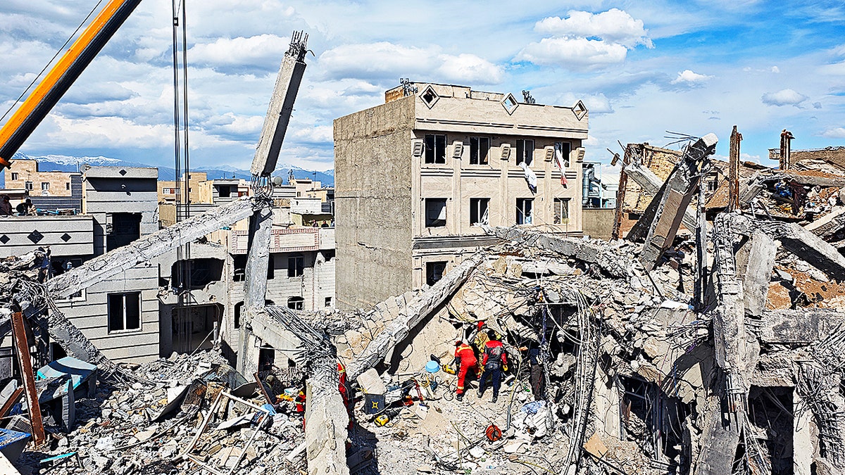 Rescue workers searching rubble of collapsed residential building in Tehran