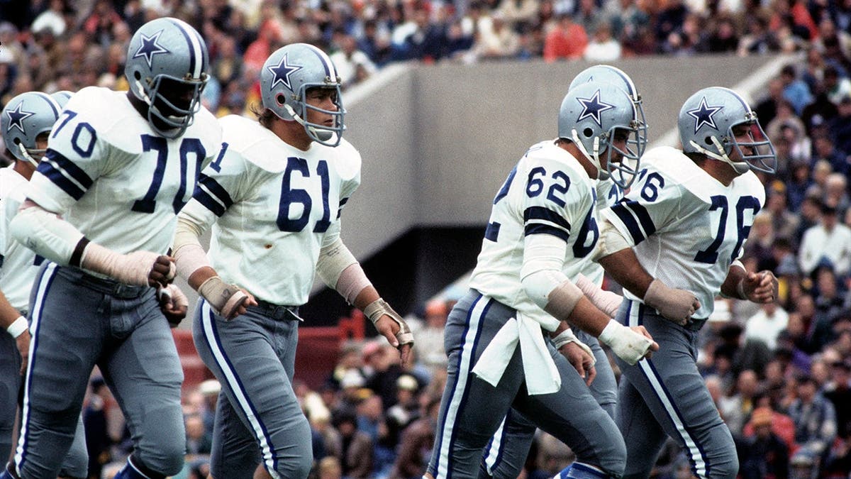 Offensive linemen Rayfield Wright, Blaine Nye, John Fitzgerald and John Niland jogging on football field.