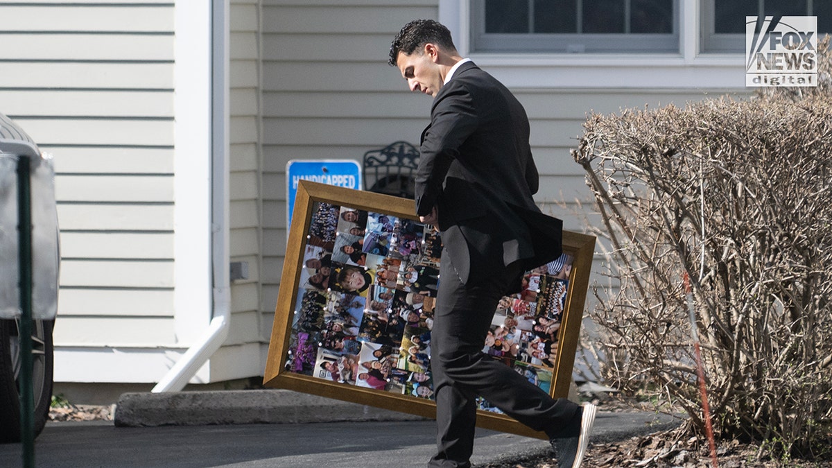 A man carries a framed collage of photos outside a memorial service for Sheridan Gorman at First Presbyterian Church of Yorktown, in Yorktown Heights, New York.