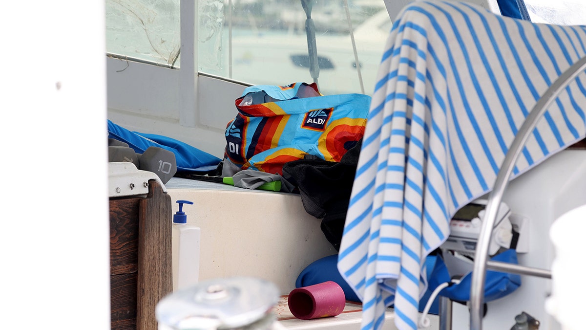 Miscellaneous items including dumbbells, a colorful bag, and a striped towel sitting inside the cabin of a boat.