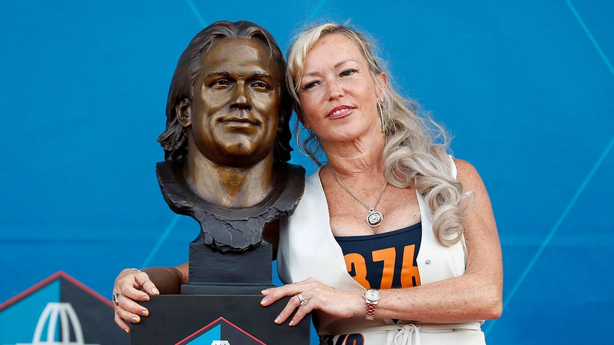 Misty McMichael posing with Steve McMichael's bust at Pro Football Hall of Fame ceremony in Canton
