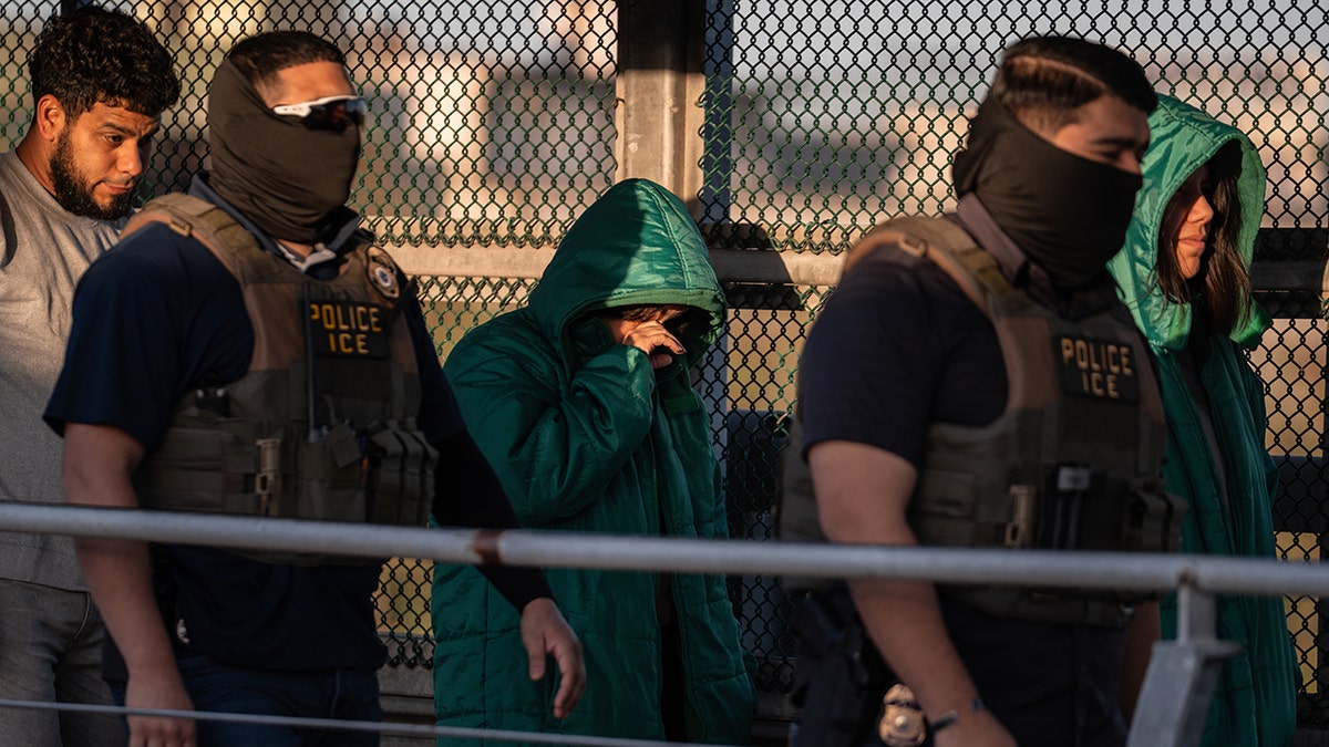 A group of undocumented migrants escorted by U.S. Immigration and Customs Enforcement agents across a bridge in McAllen, Texas