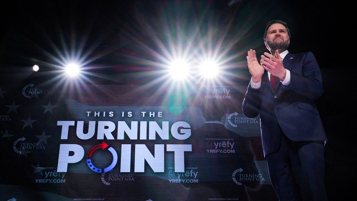 JD Vance claps during a TPUSA event on stage