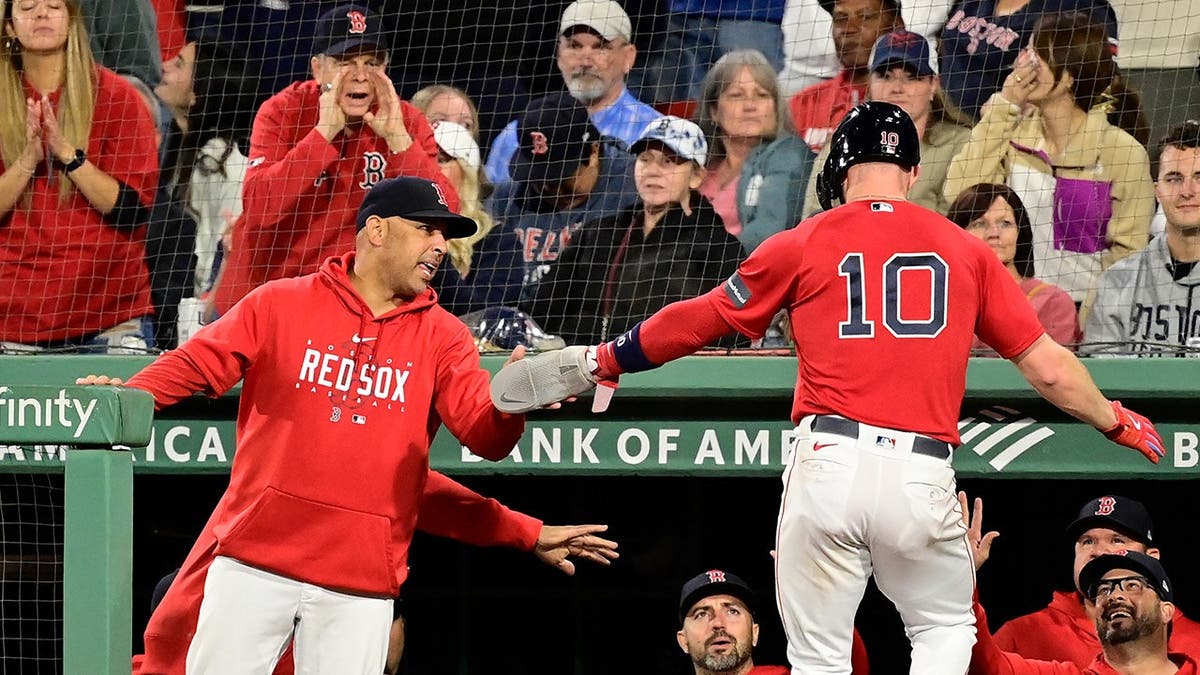 Boston Red Sox shortstop Trevor Story celebrating scoring a run with manager Alex Cora at Fenway Park