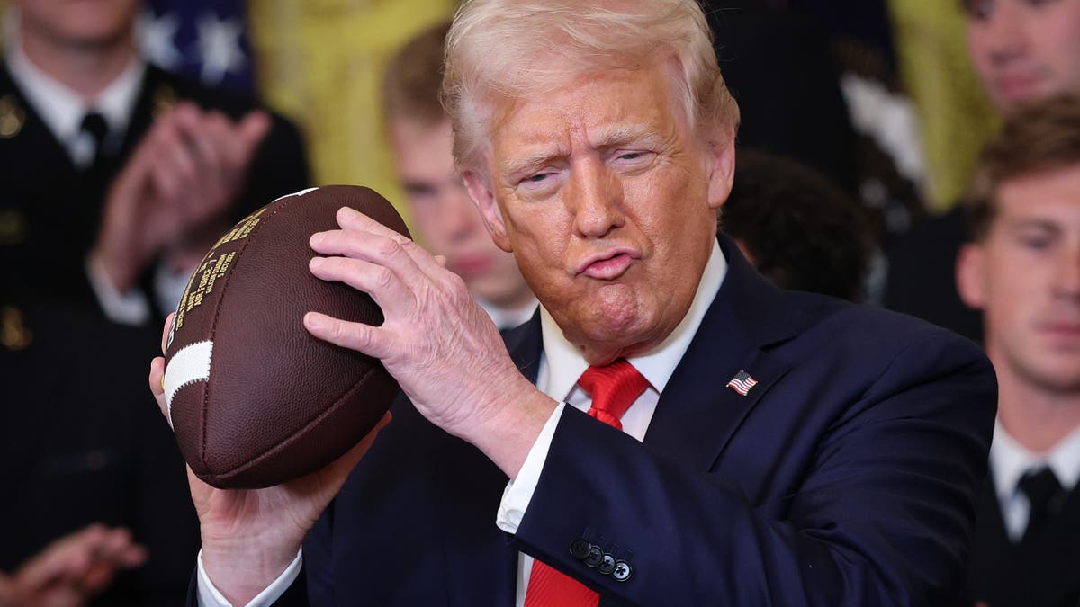 President Donald Trump holding up a football in the East Room of the White House