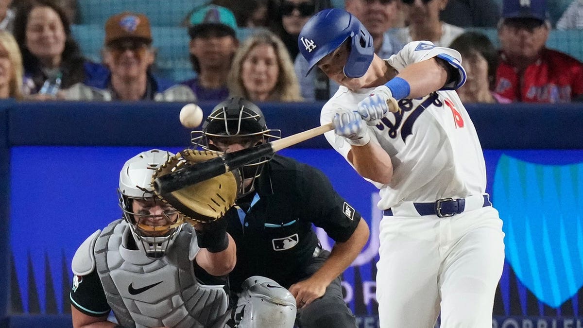 Los Angeles Dodgers' Will Smith hitting a home run as Arizona Diamondbacks catcher James McCann watches.