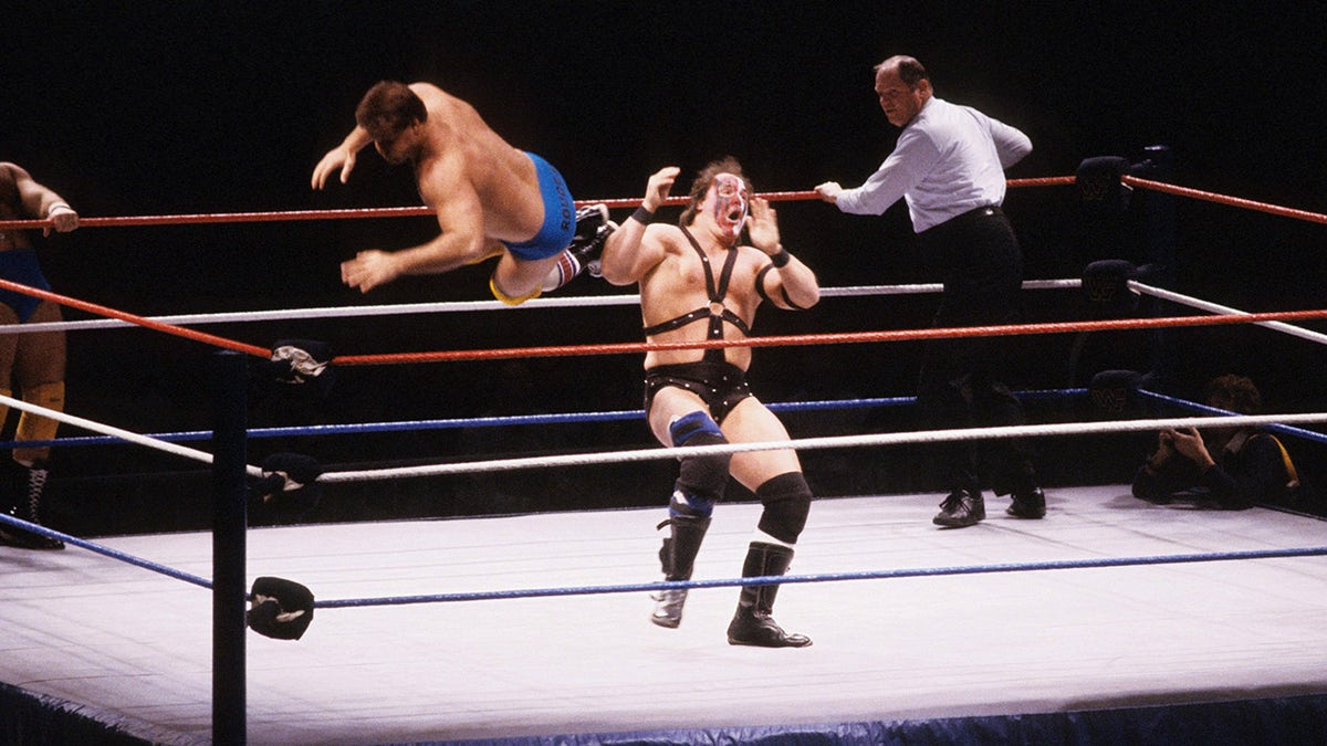 Jacques Rougeau drop kicking Smash of Demolition in a wrestling ring