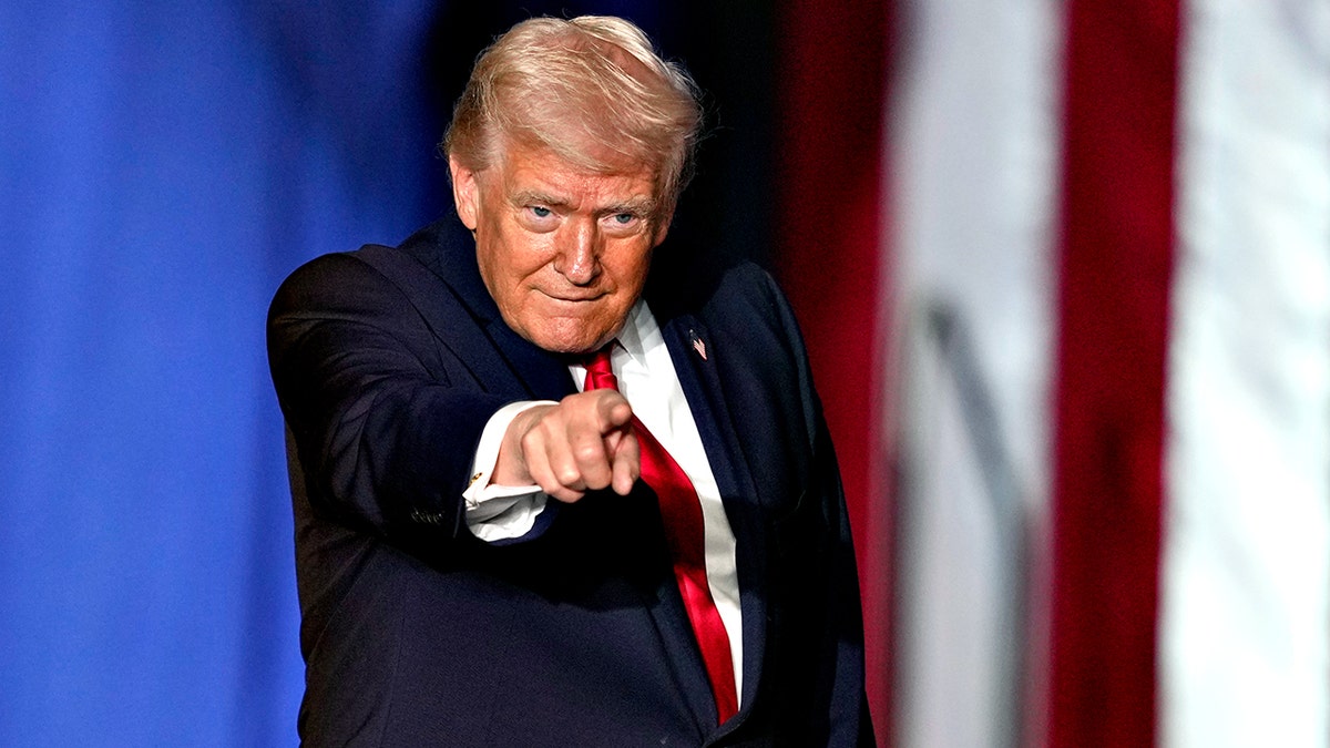 President Donald Trump pointing while speaking on stage at a rally in Clive, Iowa