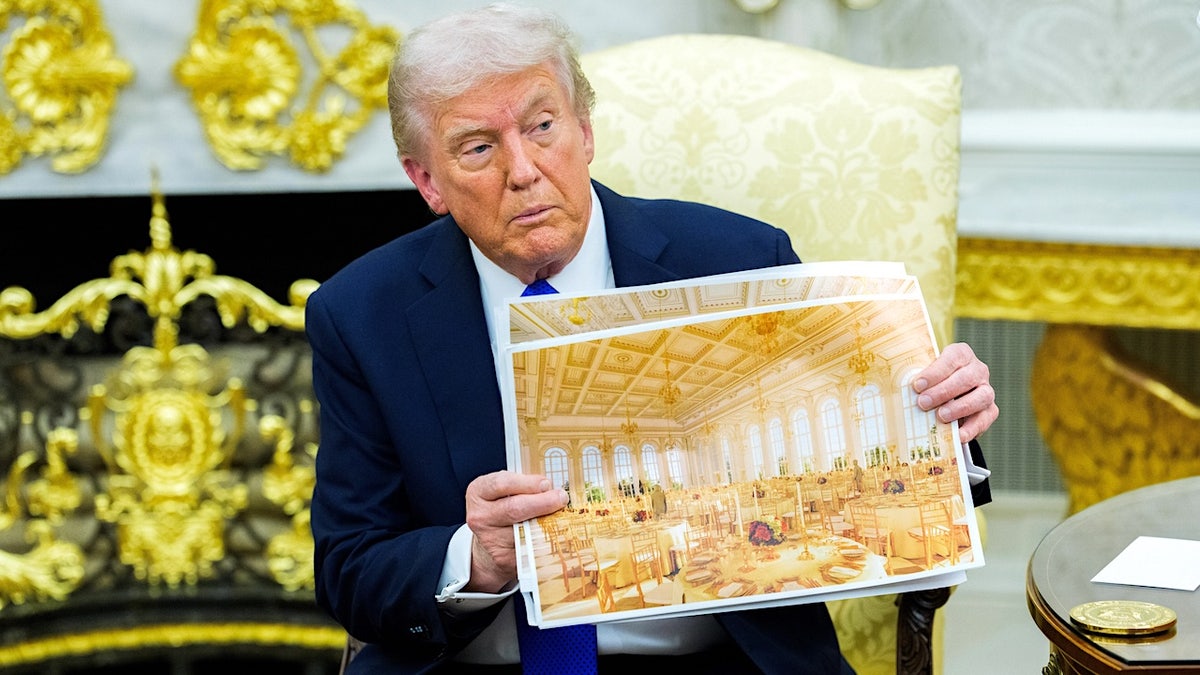 President Donald Trump holding a design rendering of a proposed White House ballroom.
