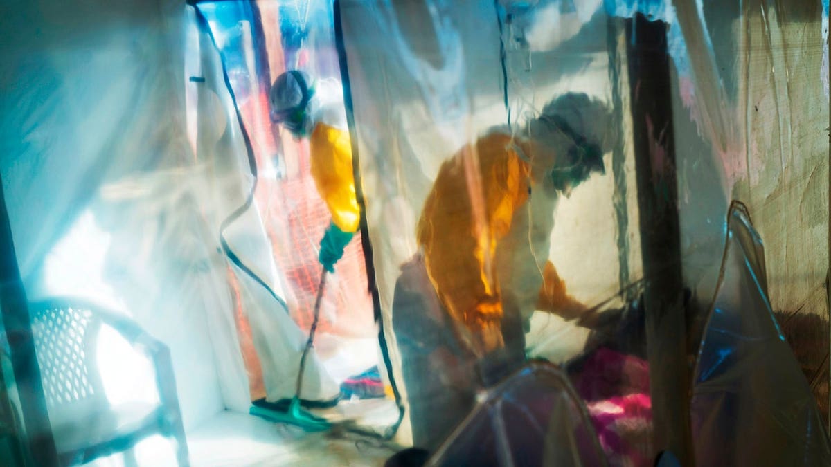 Health workers wearing protective suits tending to an Ebola victim in an isolation tent