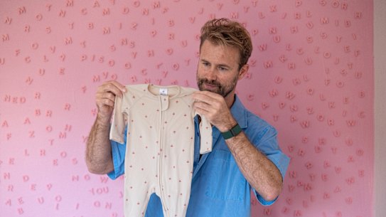 Tom Bull holds an infant’s outfit that was purchased in anticipation of welcoming his first child.
