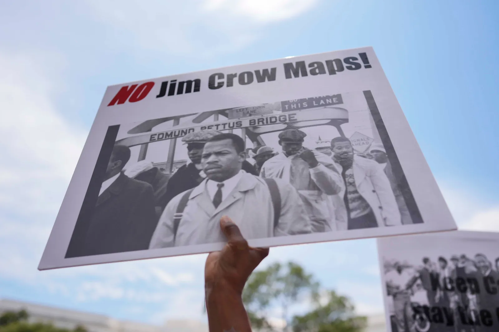 A protestor holds a sign of the late Georgia Congressman John Lewis during a voting rally on May 16 in Montgomery, Alabama. (AP Photo/Mike Stewart)