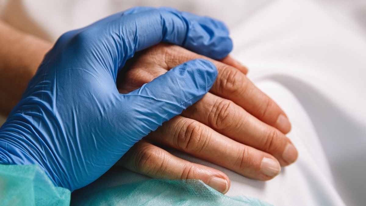 A doctor and patient holding hands in a medical setting