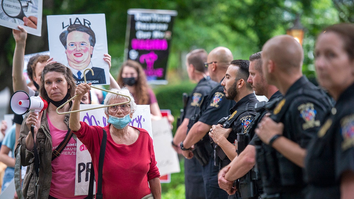 Police officers watch abortion-rights advocates demonstrating outside Brett Kavanaugh's home in Chevy Chase Maryland