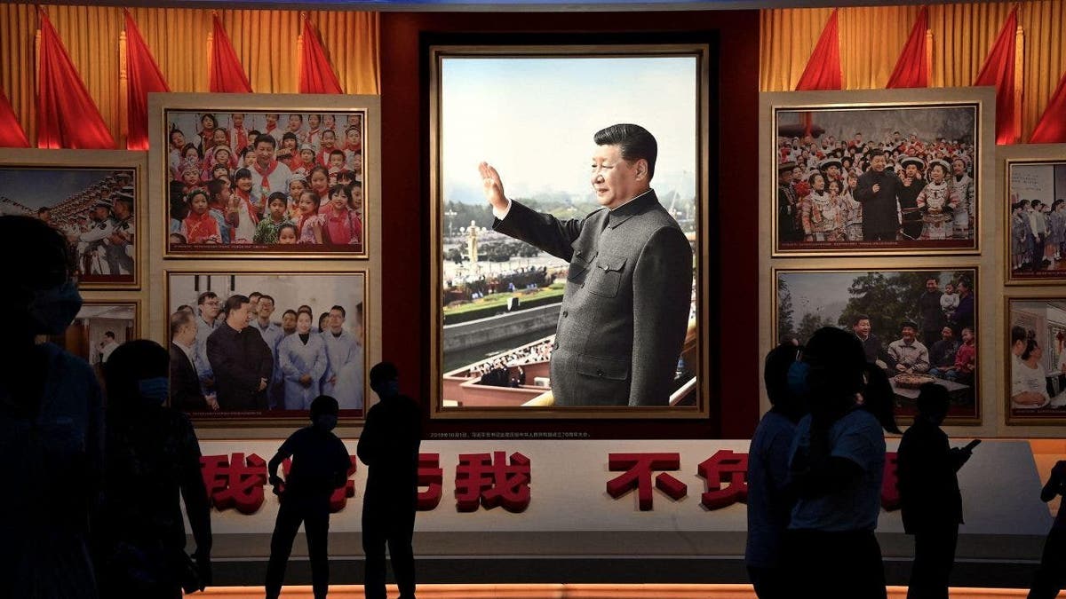 People standing in front of images of Chinese President Xi Jinping at a museum in Beijing
