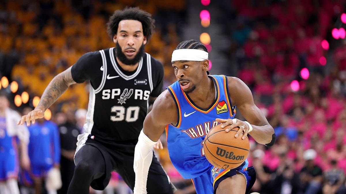 Shai Gilgeous-Alexander driving to basket past Julian Champagnie in basketball game