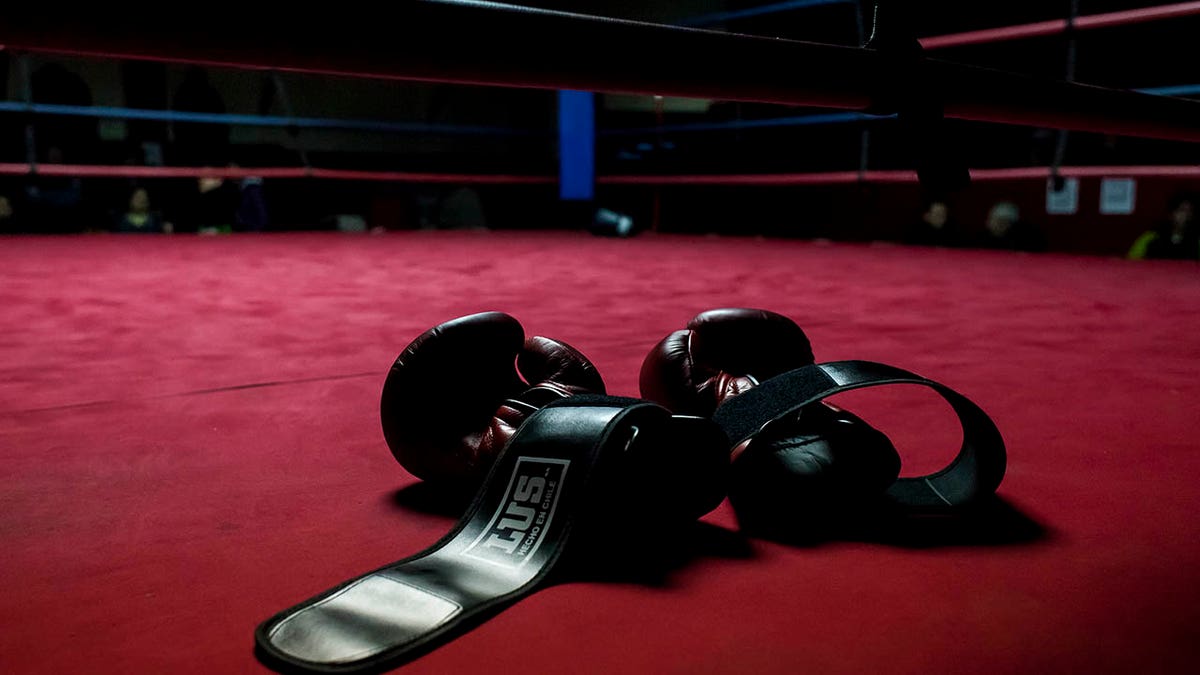 Boxing gloves laying on a mat inside a boxing ring.