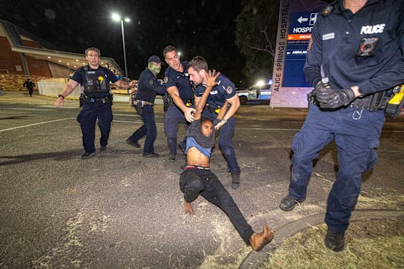 Officers pull a protester across a road outside the hospital.