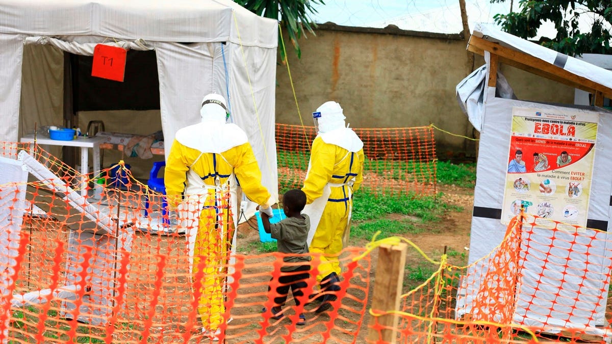 Health workers walking with a boy suspected of having Ebola at a treatment center