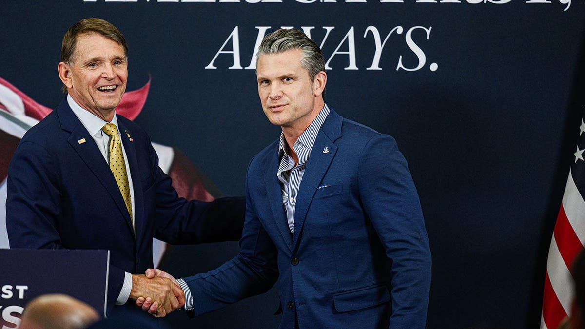 Ed Gallrein and U.S. Secretary of War Pete Hegseth greeting each other onstage