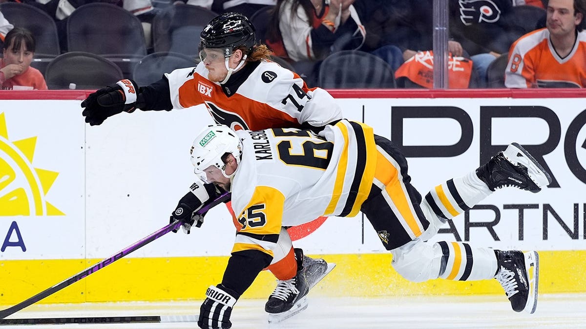 Pittsburgh Penguins' Erik Karlsson and Philadelphia Flyers' Owen Tippett chasing puck on ice rink