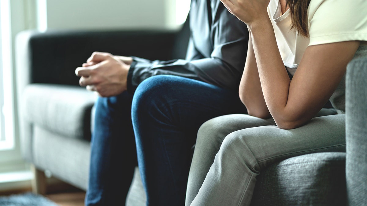 Sad upset married man and woman sitting together showing no trust