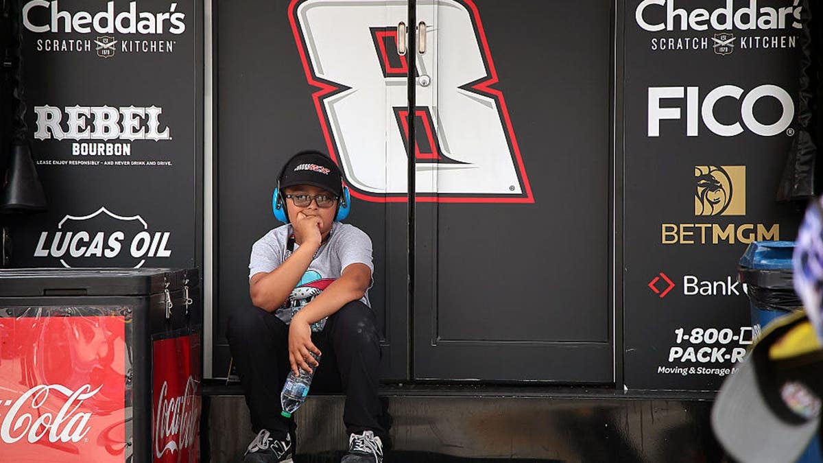 A young NASCAR fan sitting on the steps of the number 8 hauler at Charlotte Motor Speedway.