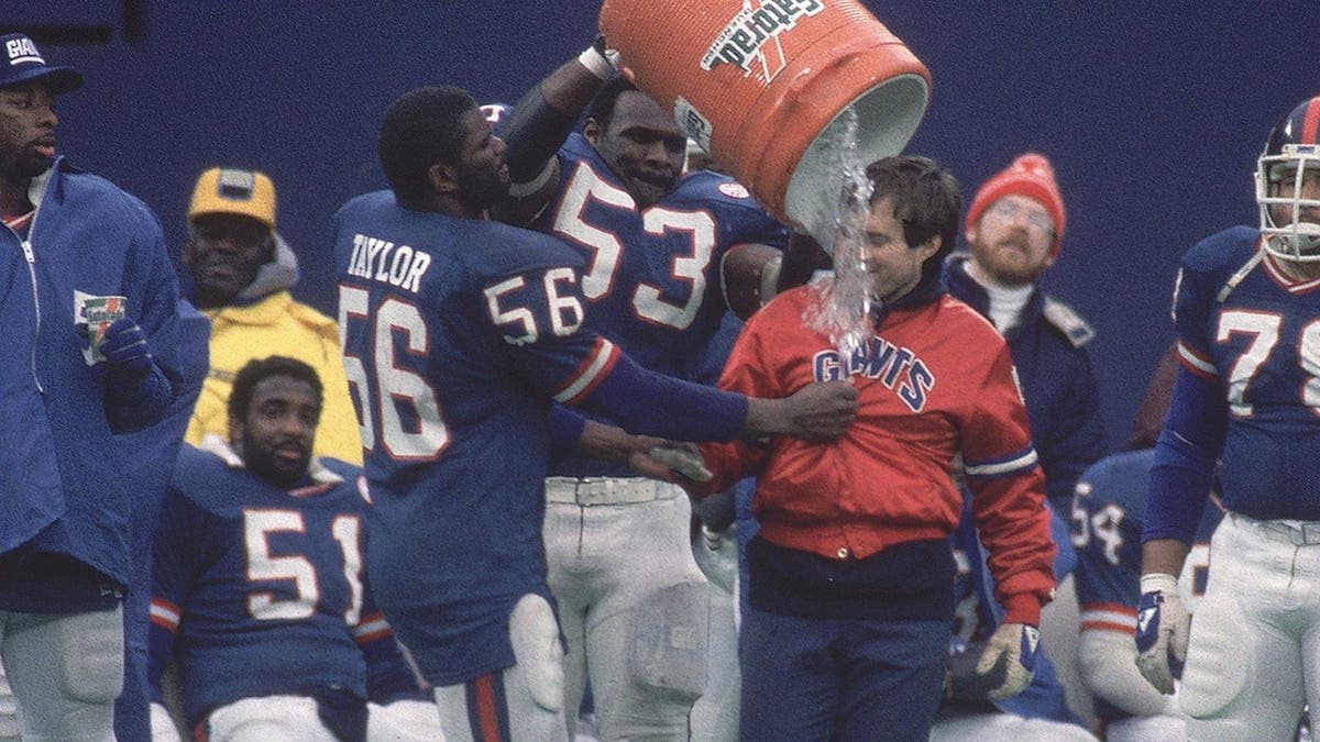 Lawrence Taylor and Bill Belichick celebrating with water bucket during football game