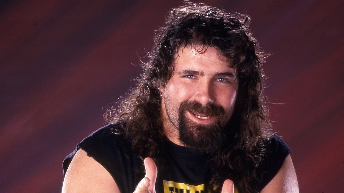 Cactus Jack Mick Foley posing for photos with WWE.