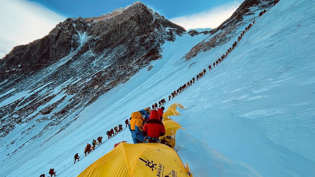 Mountaineers lined up climbing a slope on Mount Everest.