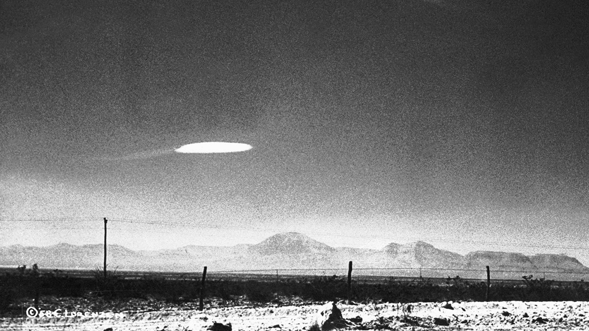 A black and white photo of a UFO hovering over a landscape in New Mexico