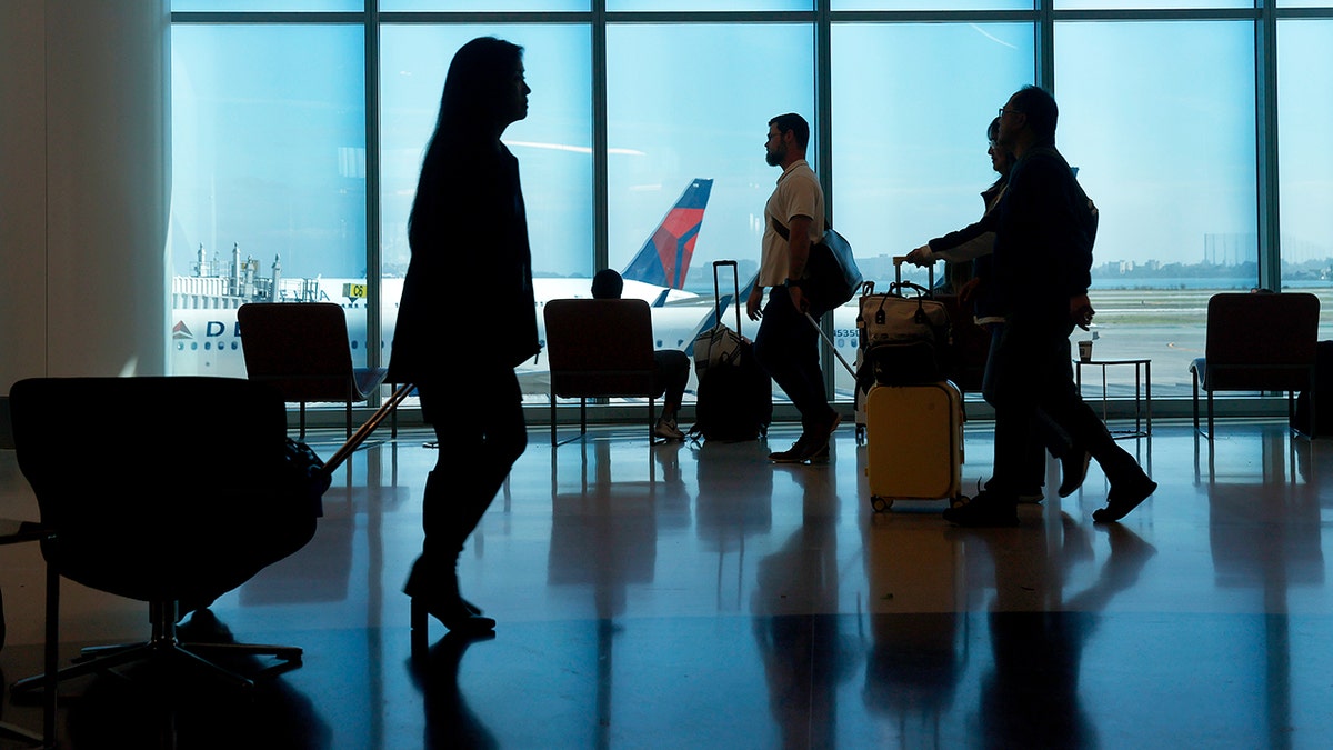 Travelers walking through Terminal 1 at San Francisco International Airport with large windows showing airfield.
