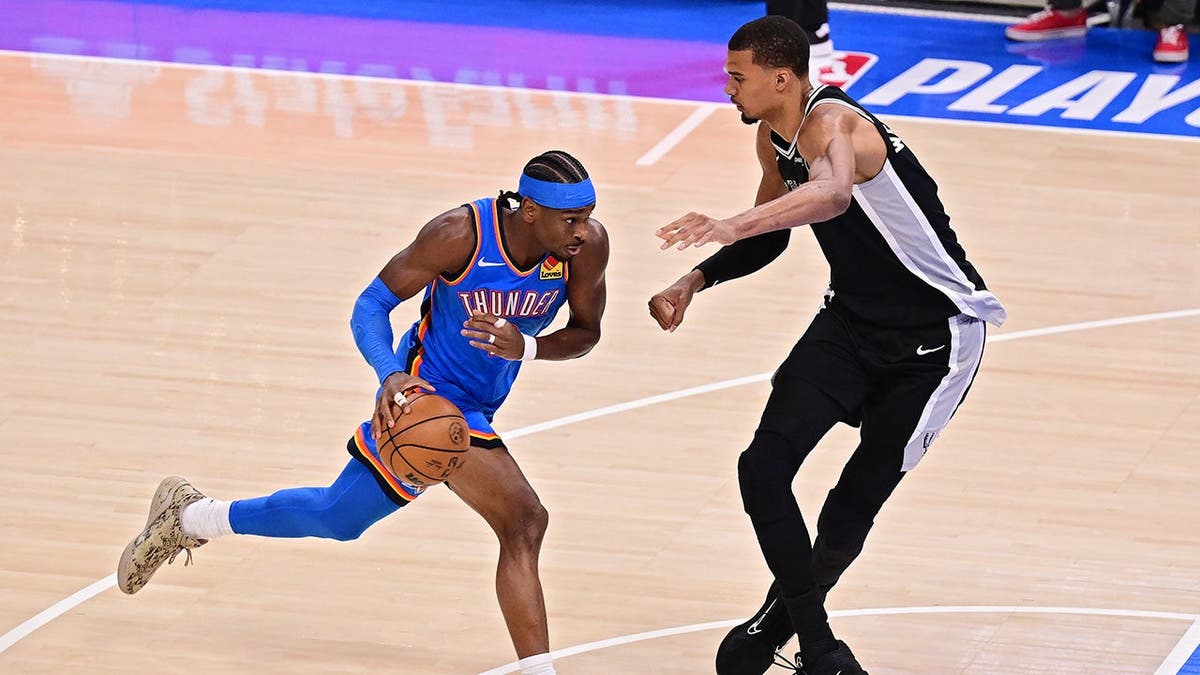 Shai Gilgeous-Alexander drives to the basket against Victor Wembanyama during NBA game.