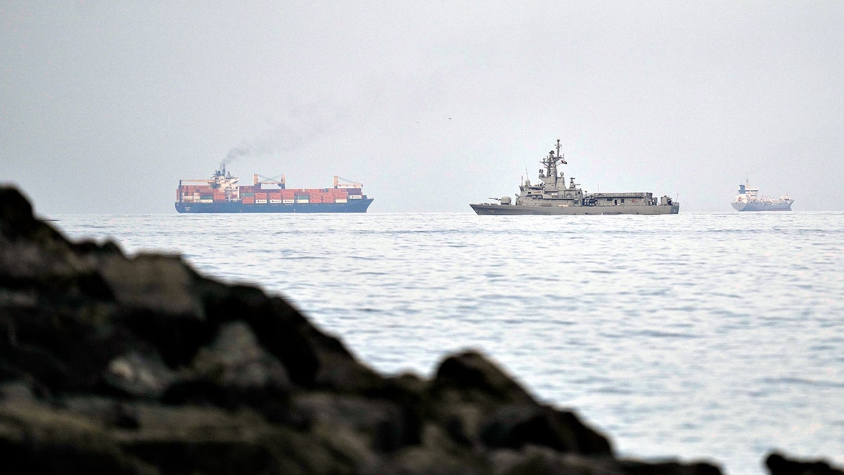 A UAE navy ship sailing next to a cargo ship in the Strait of Hormuz