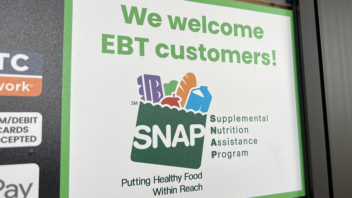 A sign at a supermarket entrance reading We Welcome EBT customers with a SNAP logo