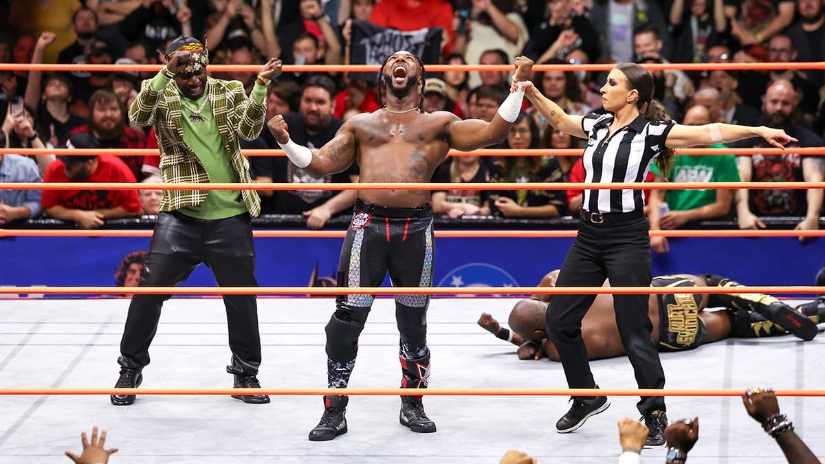 Referee Aubrey Edwards raising Swerve Strickland's hand in a wrestling ring
