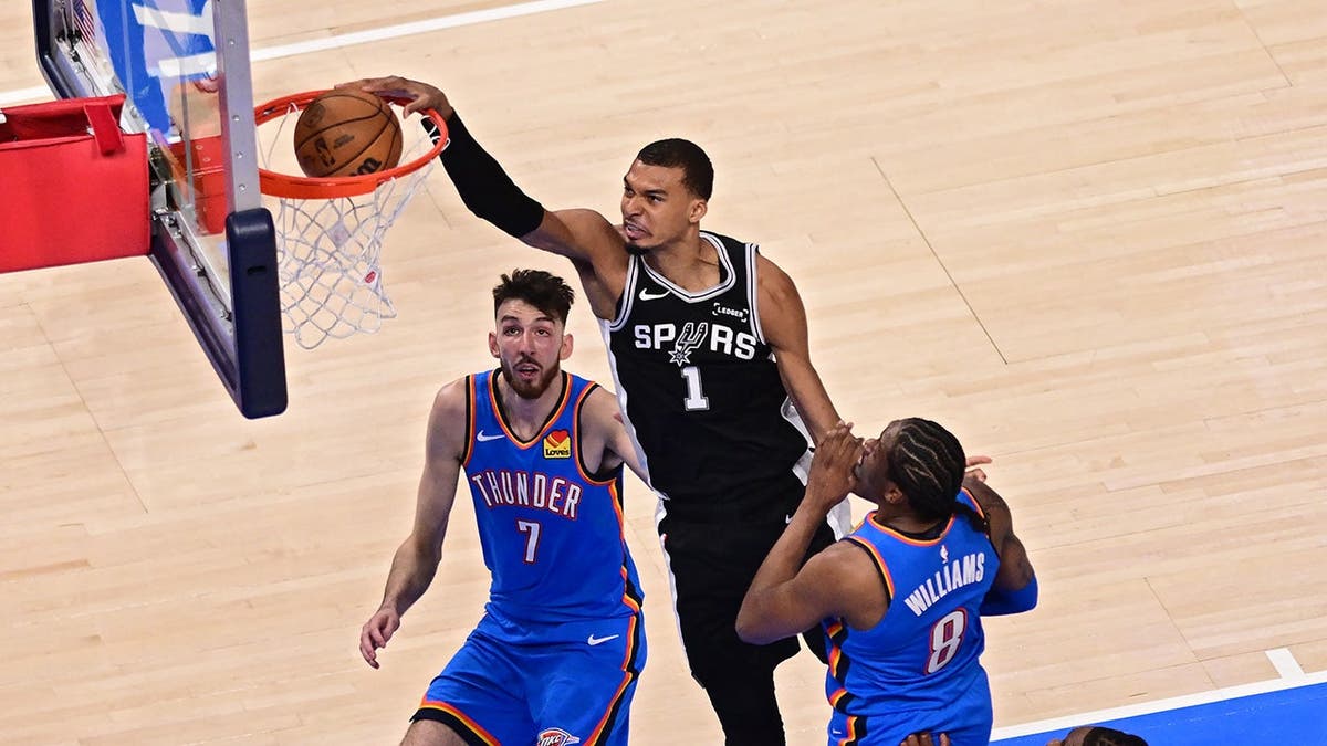 Victor Wembanyama dunks the ball against Chet Holmgren and Jalen Williams during NBA game
