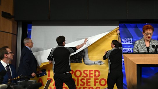 Press Club staff remove a banner seen behind One Nation leader Pauline Hanson, June 17, 2026.