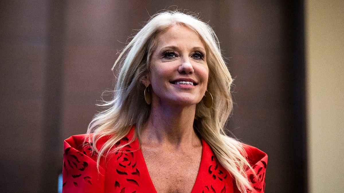 Kellyanne Conway standing at a podium speaking at the America First Agenda Summit.