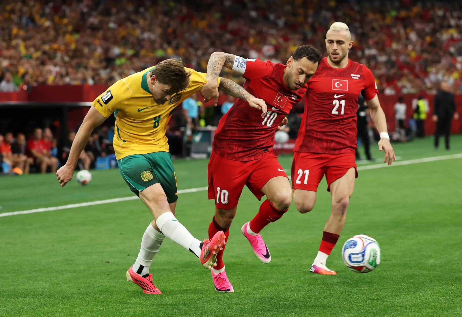 VANCOUVER, BRITISH COLUMBIA - JUNE 13: Connor Metcalfe #8 of Australia passes the ball under pressure from Hakan Calhanoglu #10 of Turkiye during the FIFA World Cup 2026 Group D match between Australia and Türkiye at BC Place Vancouver on June 13, 2026 in Vancouver, British Columbia. (Photo by Stu Forster/Getty Images)