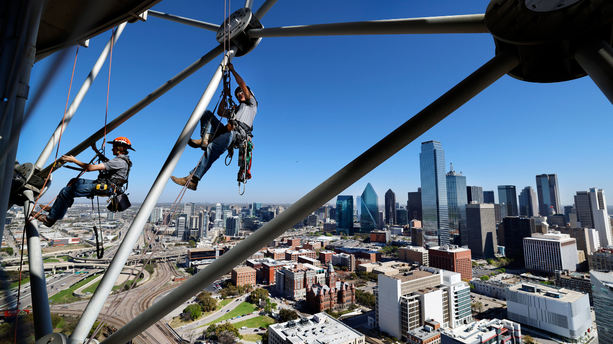 Workers are seen climbing the Reunion Tower in downtown Dallas, Texas.