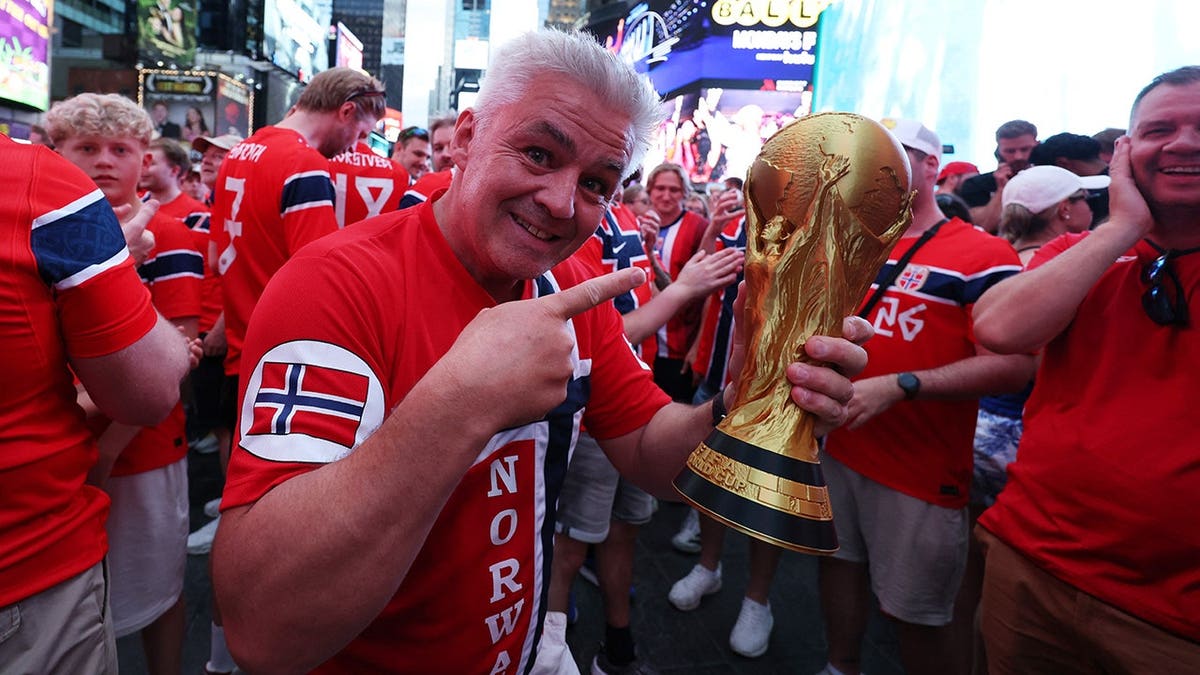 A Norway fan holding a replica FIFA World Cup trophy in Times Square New York