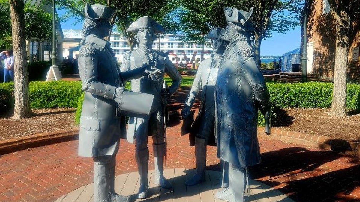 Four statues in colonial clothing face each other.