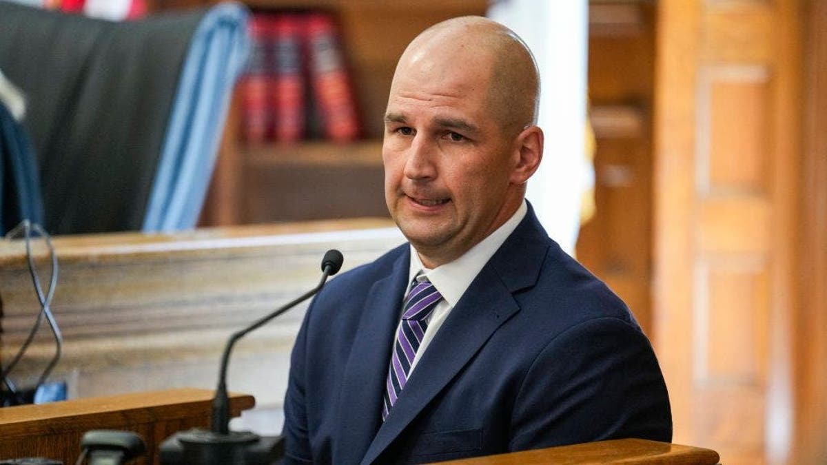 Massachusetts State Police Trooper Michael Proctor testifies on the witness stand in a courtroom.