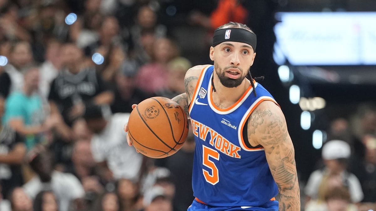 New York Knicks guard Jose Alvarado dribbling basketball against San Antonio Spurs in arena