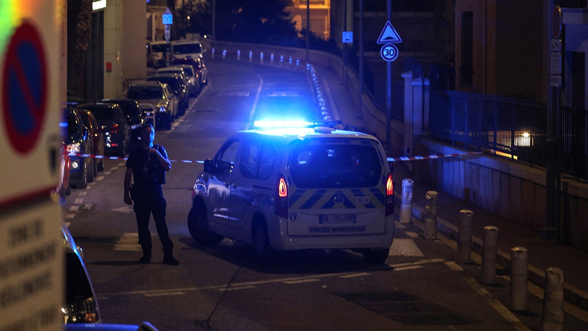 A police officer stands guard next to a police car after setting up a security perimeter on a street following an explosion that occurred in a residential building in Monaco